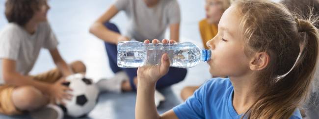 Niña deportista tomando agua.