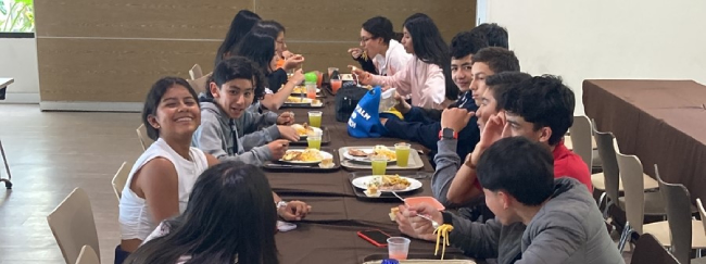 Imagen en mesa redonda de niños en descanso mientras comparten las onces.